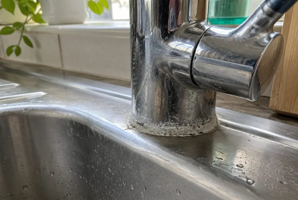 Limescale build-up around a chrome kitchen tap